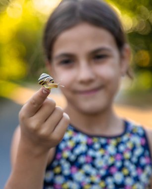 A child is studying a snail in the park. Selective focus. Nature.