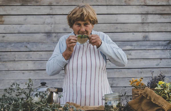 Grandmother makes tea with medicinal herbs. Selective focus. Nature.