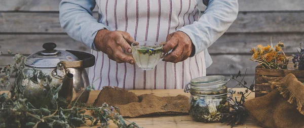 Grandmother makes tea with medicinal herbs. Selective focus. Nature.