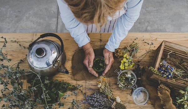 Grandmother makes tea with medicinal herbs. Selective focus. Nature.