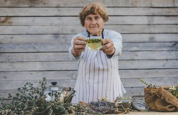 Grandmother makes tea with medicinal herbs. Selective focus. Nature.