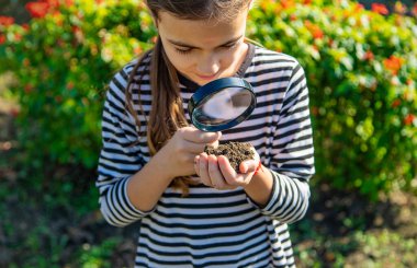 Çocuklar toprağı bir büyüteçle incelerler. Seçici odaklanma. Çocuk.