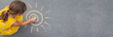 Çocuk asfalta güneşi çizer. Seçici odaklanma. Doğa.