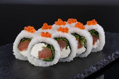 Ton balığı ve krem peynirle yuvarlan. Siyah arka planda suşi ve rulo..