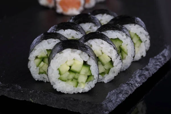 キュウリとお米で転がす 黒を基調とした寿司と巻き寿司 — ストック写真