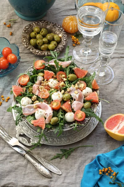 Meyveli salata, pastırma ve şarap gri arka planda.