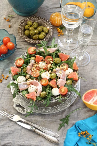 Meyveli salata, pastırma ve şarap gri arka planda.