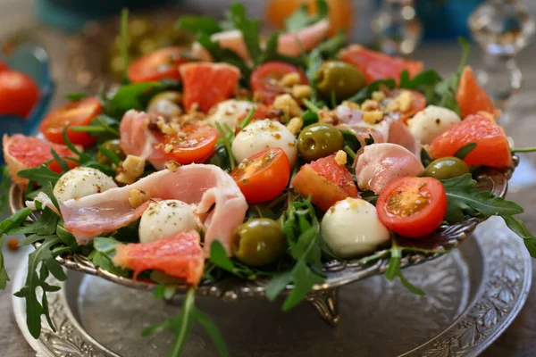 Meyveli salata, pastırma ve şarap gri arka planda.