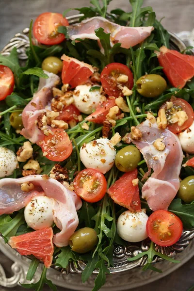 Meyveli salata, pastırma ve şarap gri arka planda.