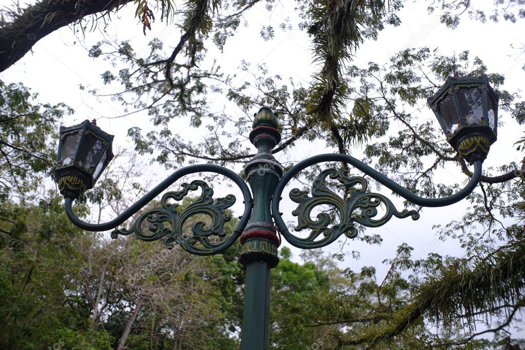 Soaring decorative garden lights are placed in a beautiful public park full of trees.