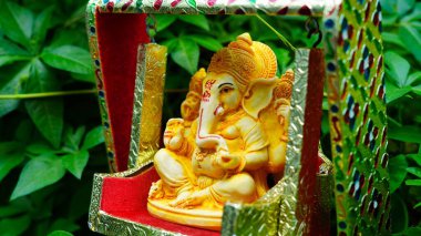 Lord Ganesha idol sitting in decorated swing in Ganesh Chaturthi festival in India. The Elephant god statue with nature background. Also known Vinayaka Chaturthi, Pillaiyar