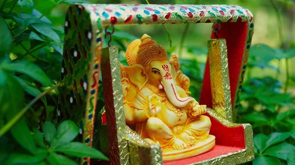 Lord Ganesha idol sitting in decorated swing in Ganesh Chaturthi festival in India. The Elephant god statue with nature background. Also known Vinayaka Chaturthi, Pillaiyar