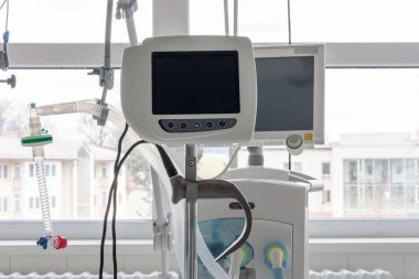 Hastanedeki yoğun bakımda arka plandaki tıbbi solunum cihazında laringoskop var. Doktorları hastalardan uzak tutmak için ayrı ekranlı laringoskop..