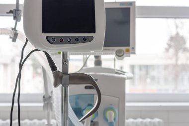 Hastanedeki yoğun bakımda arka plandaki tıbbi solunum cihazında laringoskop var. Doktorları hastalardan uzak tutmak için ayrı ekranlı laringoskop..