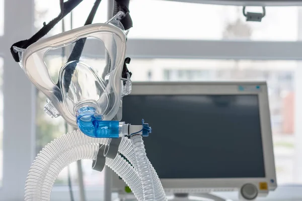 Non-invasive ventilation face mask, on background medical ventilator in ICU in hospital.