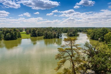 Lednice-Valtice kompleksi, Minaret-gözlem kulesinden kale göleti manzarası, ağaçlı park ve Lednice kalesi.