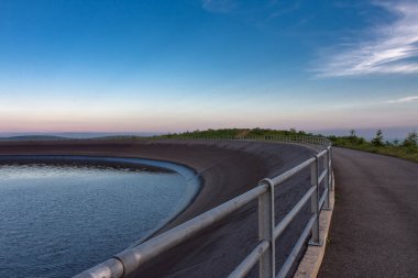 Çek Cumhuriyeti 'nin Jeseniky Dağları' ndaki pompalı depolama hidroelektrik santrali Dlouhe Strane 'in üst su deposu. Yaz akşamları, mavi gökyüzü ve bulutlarla gün batımı