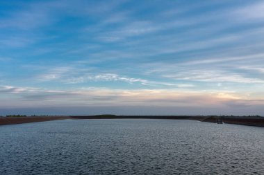 Çek Cumhuriyeti 'nin Jeseniky Dağları' ndaki pompalı depolama hidroelektrik santrali Dlouhe Strane 'in üst su deposu. Yaz akşamları, mavi gökyüzü ve bulutlarla gün batımı.