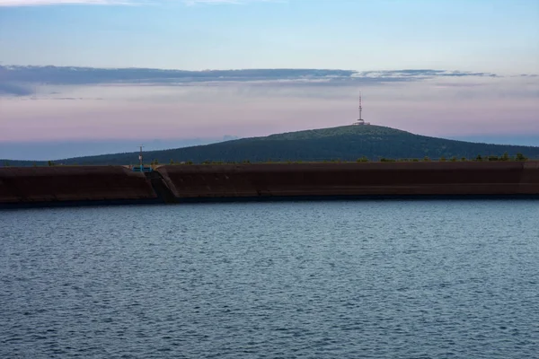 Upper water reservoir of the pumped storage hydro power plant Dlouhe Strane in Jeseniky Mountains, Czech Republic. Top of the Praded mountain behind the lake. During summer evening, sunset .