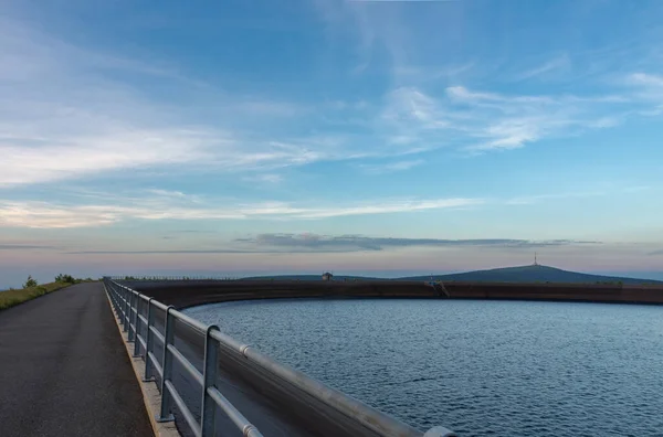 Upper water reservoir of the pumped storage hydro power plant Dlouhe Strane in Jeseniky Mountains, Czech Republic. Top of the Praded mountain behind the lake. During summer evening, sunset.