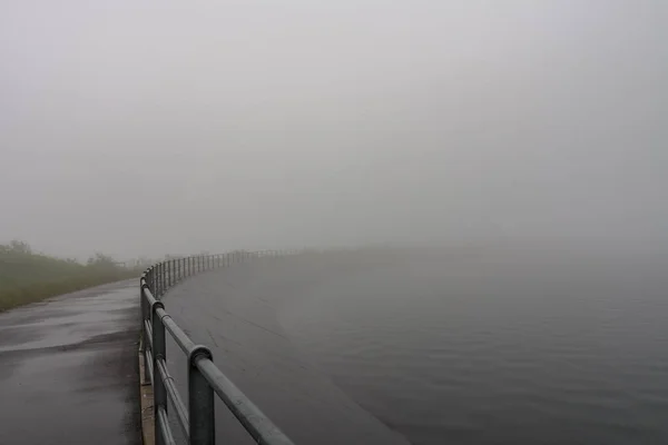 Upper water reservoir of the pumped storage hydro power plant Dlouhe Strane in Jeseniky Mountains, Czech Republic. During summer foggy rainy morning,