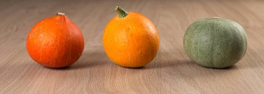 Ahşap bir masanın üstünde art arda taze balkabakları, afiş. Kırsal tarzda. Şükran Günü ve Cadılar Bayramı konsepti.