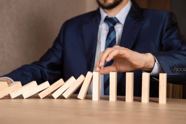 İş adamı eli Düşen Tahta Dominoların sürekli devrilmesinden ya da risk almasından, strateji ve iş için başarılı müdahale kavramının etkilerini durdurur.