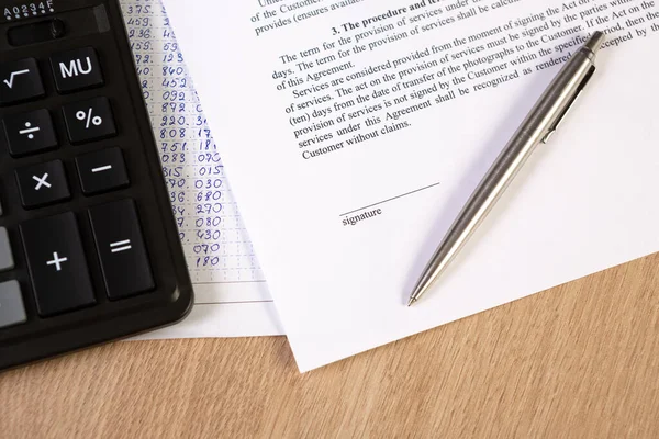 A part of contract or agreement document, space of signature with a silver pen and calculator.