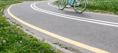 Yeşil tekerli bisiklet süren bir kadın parktaki işaretli bisiklet yolunda