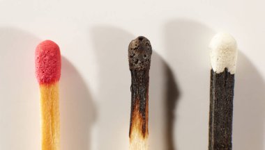 Wooden matche with red head, black wooden matche with white head and burnt match on a light gray background close-up. Matchsticks without box.