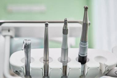 Diş matkabı kapatılıyor ve dişçi koltuğunda diğer dişçi aletleri var..