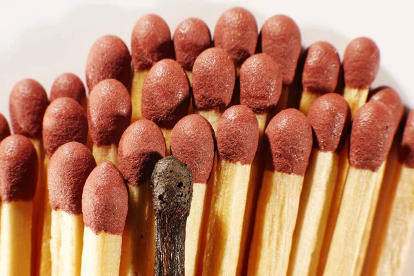 Burnout syndrome, stress, exhaustion and work-life balance concept. Close-up of a single burnt match in a group of matches.