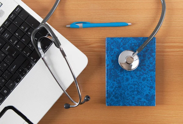 Stetoskop, bilgisayar, defter ve tahta arka planda kalem. Doktor masası..