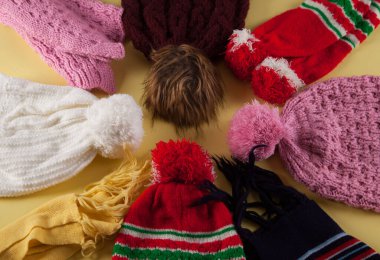 İzole edilmiş sarı arka planda renkli sıcak kış şapkaları.. 