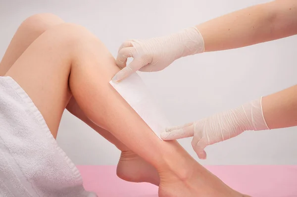 Spa professional doing waxing. Woman waxing her legs. Skin and personal care concept. Spa and beauty center