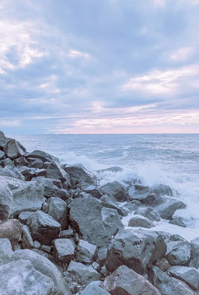 Waves splash over the rocks in soft pastel colors in Batumi, Georgia.