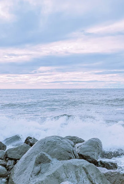 Waves splash over the rocks in soft pastel colors in Batumi, Georgia.