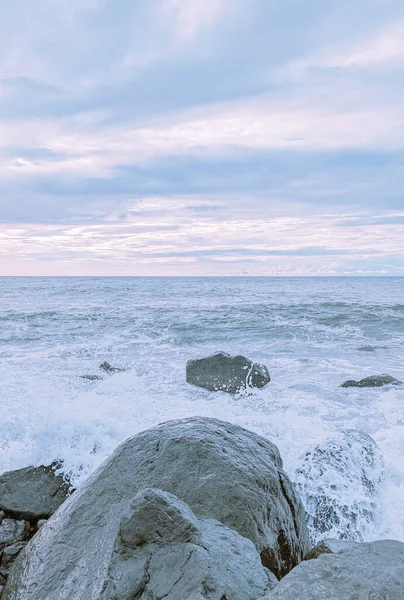 Waves splash over the rocks in soft pastel colors in Batumi, Georgia.