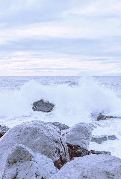 Waves splash over the rocks in soft pastel colors in Batumi, Georgia.