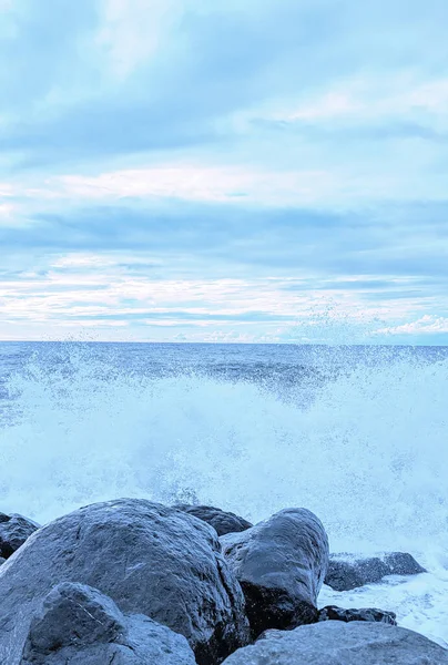 Waves splash over the rocks in soft pastel colors in Batumi, Georgia.