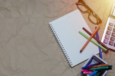 Kahverengi bir Kraft kağıdında boş bir defter ve gözlük.