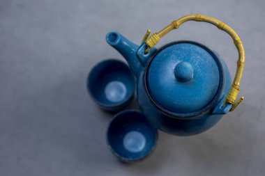 Mavi seramik çaydanlık ve bulanık gri arka planda çay fincanı. Metin girmek için boşluk ile