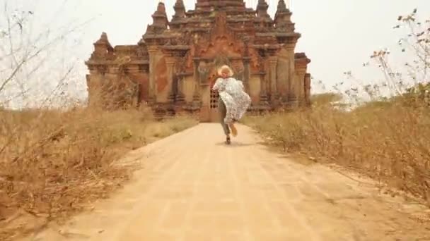 Giovane donna turistica che corre in abito bianco al vecchio tempio birmano tradizionale. Viaggio Avventura Stile di vita Concetto di vacanza. 4K Slowmotion Steadycam Seguimi Filmato. Bagan, Myanmar. — Video Stock