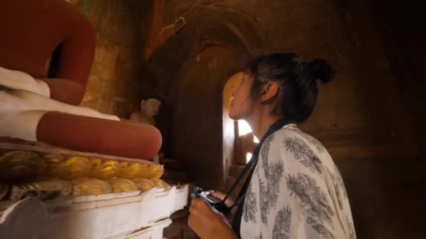 Turistkvinna tar foto av gamla Buddha staty i traditionella burmesiska templet. Buddhismen Religion resor Begreppsfilm. 4K Slowmotion. Bagan, Myanmar. — Stockvideo