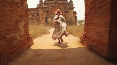 Beyaz Elbiseli Genç Turist Kadın Eski Burma Tapınağına koşuyor. Seyahat Macerası Yaşam Tarzı Tatil Konsepti. 4K Slowmotion Steadycam Beni Takip Et Görüntüsü. Bagan, Myanmar..