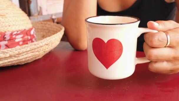 Vrouw die thee of koffie drinkt uit Cup with Red Heart. Vrouwelijke Hand nemen Metal mok van tafel in Cafe. Valentijnsdag concept 4K Slowmotion Beelden. — Stockvideo