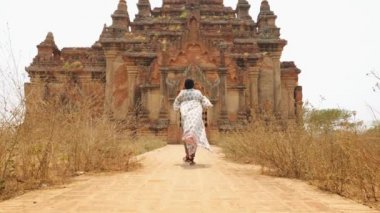 Genç Turist Kadın Waling 'den Eski Burma Tapınağına ve Kamerada Fotoğraf Çekiyor. Seyahat Macerası Yaşam Tarzı Tatil Konsepti. 4K Slowmotion Steadycam Beni Takip Et Görüntüsü. Bagan, Myanmar..