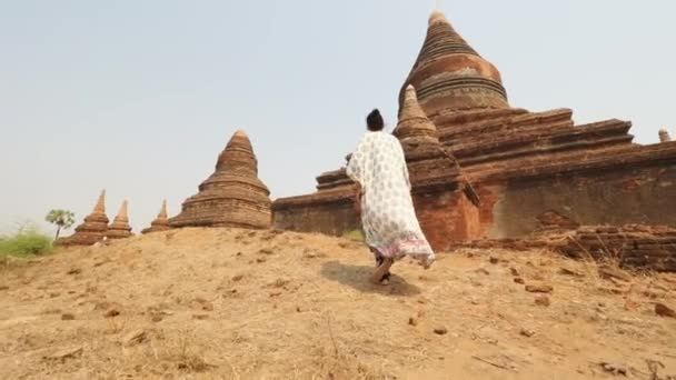 Toeristische vrouw wandelen langs oude traditionele Birmaanse tempels. Reizen vakantie Aziatische natuur Concept Beelden. 4K Slowmotion Steadycam Beelden. Bagan, Myanmar. — Stockvideo