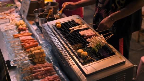 Místní asijské pouliční jídlo: kuchař vaření tradiční thajské satay na grilu v noci potravin trhu. Phuket Town, Thajsko. 4K Slowmotion Vysoce kvalitní video. — Stock video