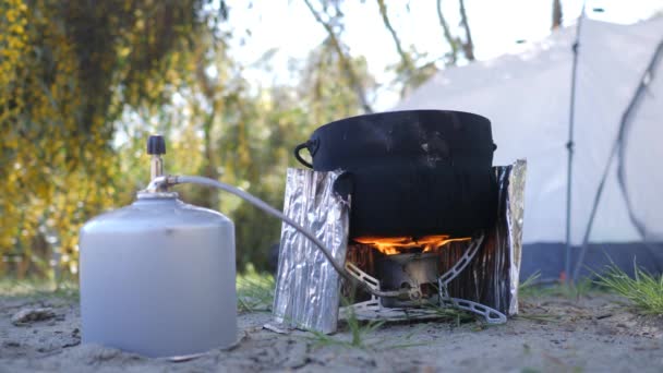 ポータブルガスストーブを使用したキャンプポットでの調理食品。外は無料の4Kコンセプト — ストック動画